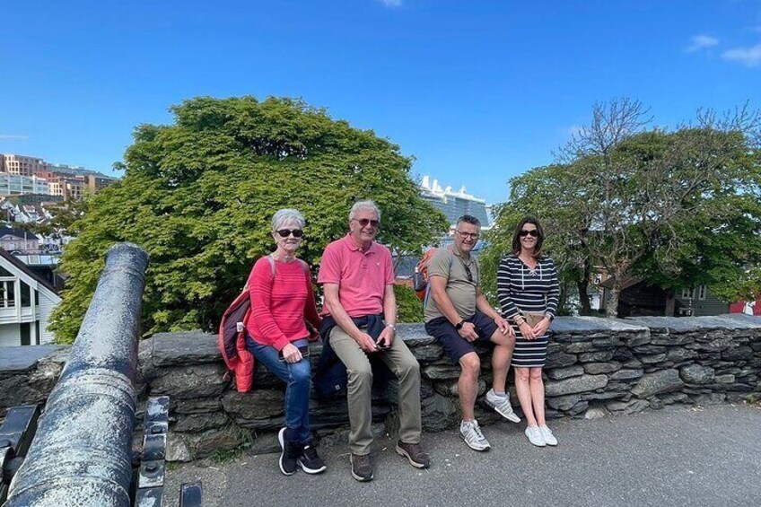 Four people sitting on a stone wall with a cannon in the foreground and a bridge in the background. 5