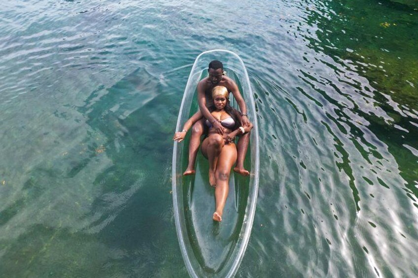 A person sitting on a transparent boat in clear water. 4