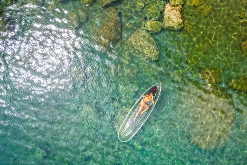 A person on a paddleboard in clear water with rocks. 5