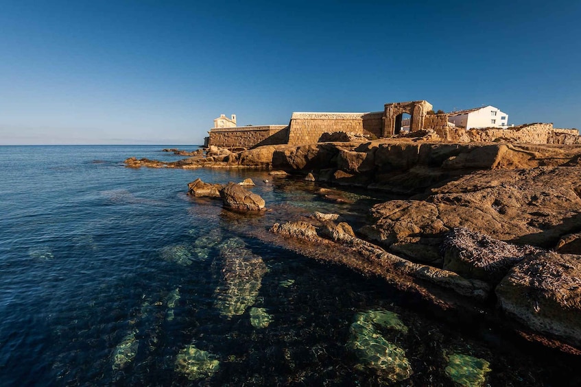 Ruinas antiguas junto a una costa rocosa con aguas azules cristalinas. 5