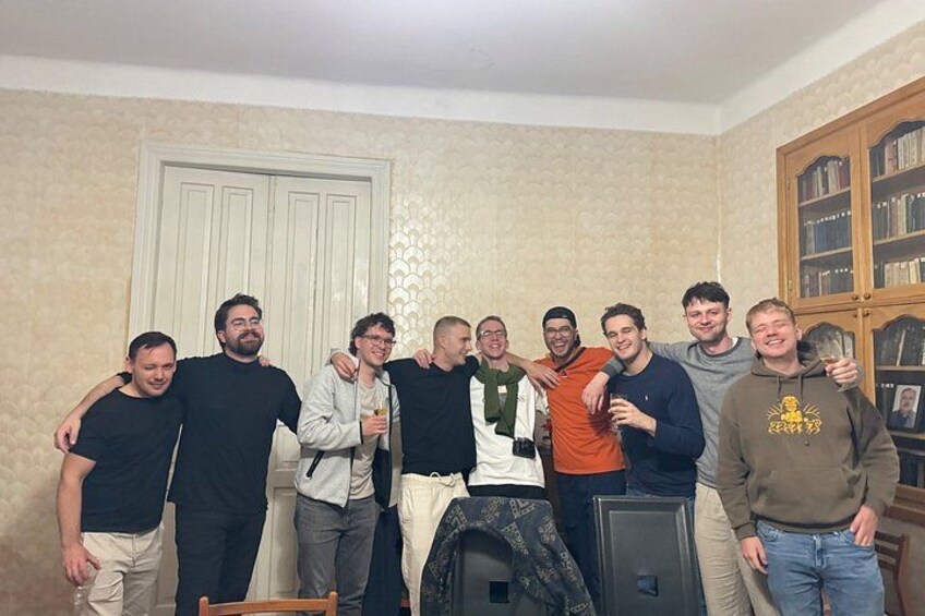 A group of people posing in a room with a bookshelf and a door in the background. 1