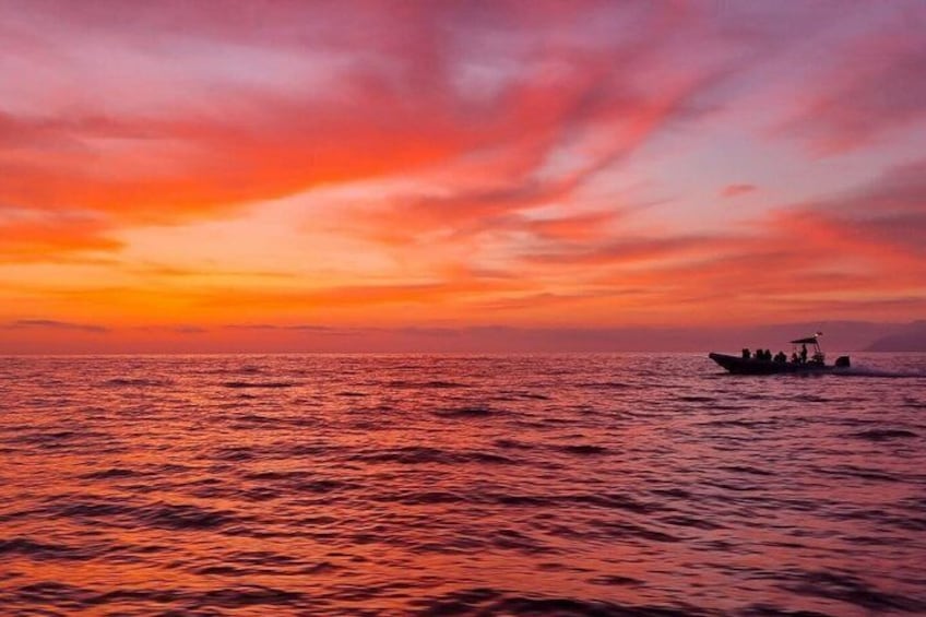 A sunset over the ocean with a boat in the distance. 3