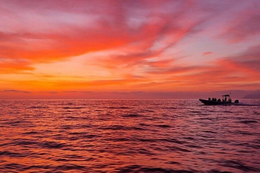 A sunset over the ocean with a boat in the distance. 3