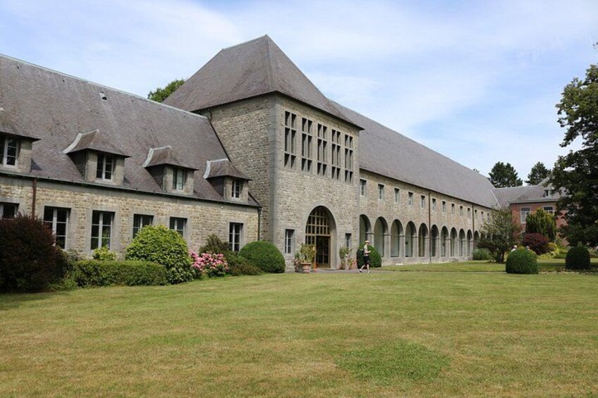 Ein großes Steinhaus mit Innenhof, umgeben von gepflegten Rasenflächen und Bäumen. 2