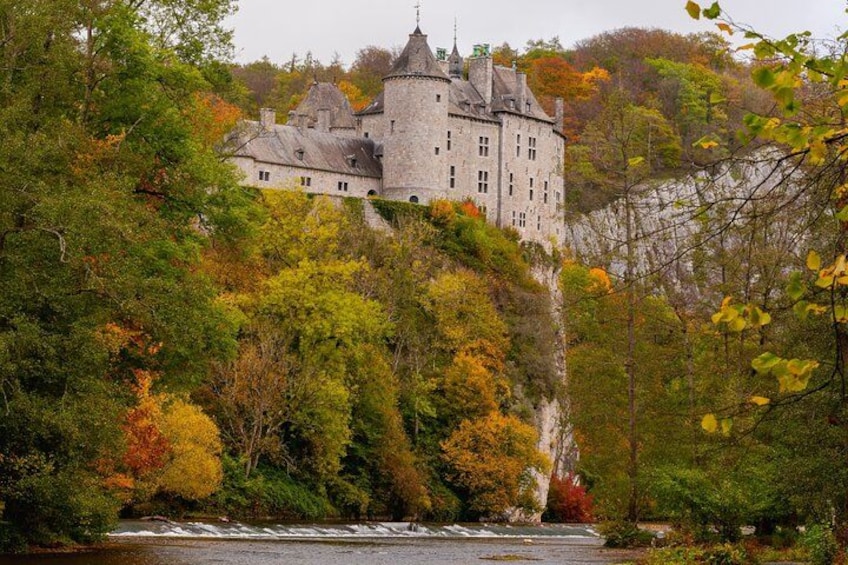 A castle on a cliff overlooking a river, surrounded by autumn foliage. 2
