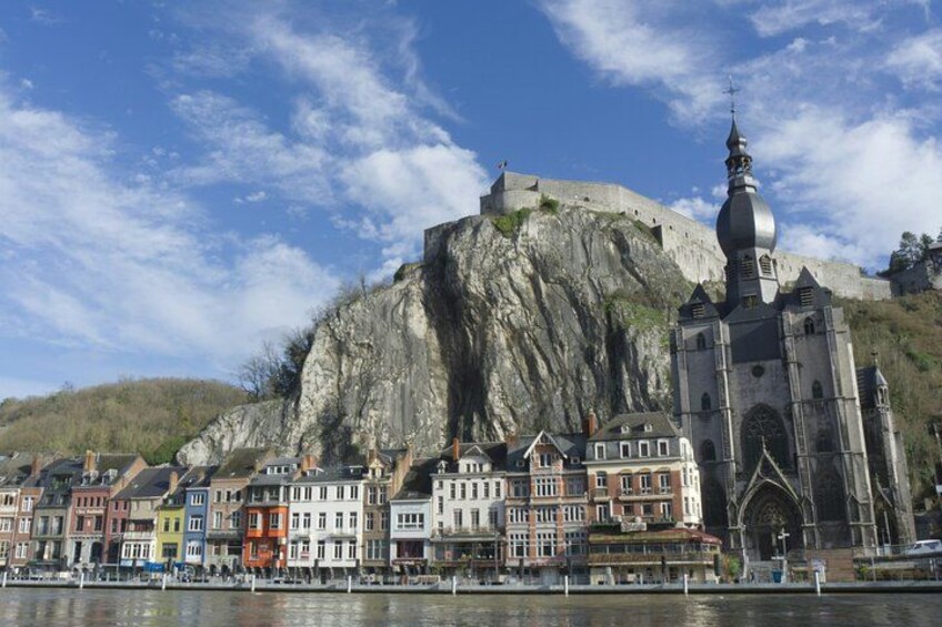 A historic town with colorful buildings, a prominent church, and a large fortification on a hill. 1