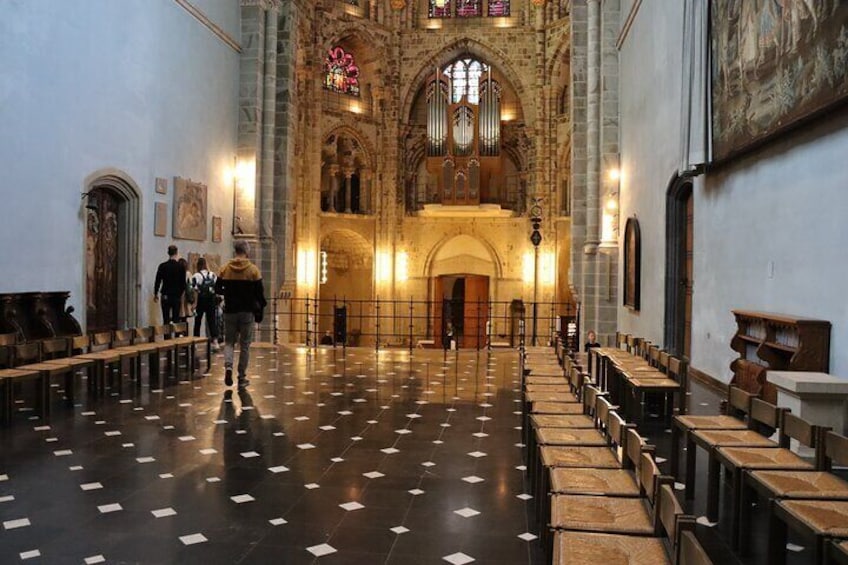 An interior of a church with rows of pews, a high vaulted ceiling, and stained glass windows. 2