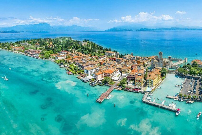An aerial view of a coastal town with a castle, clear turquoise waters, and a marina. 5