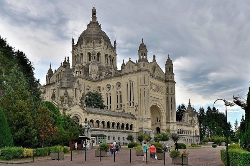 Un edificio grande y ornamentado con múltiples cúpulas y arcos, rodeado de jardines y senderos bien cuidados. 1