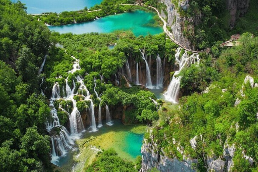 A multi-tiered waterfall cascading into a turquoise lake surrounded by lush greenery. 1