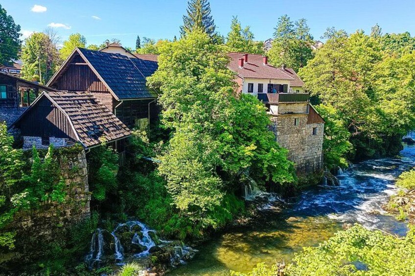 A river flowing through a forested area with houses built on stilts over the water. 5