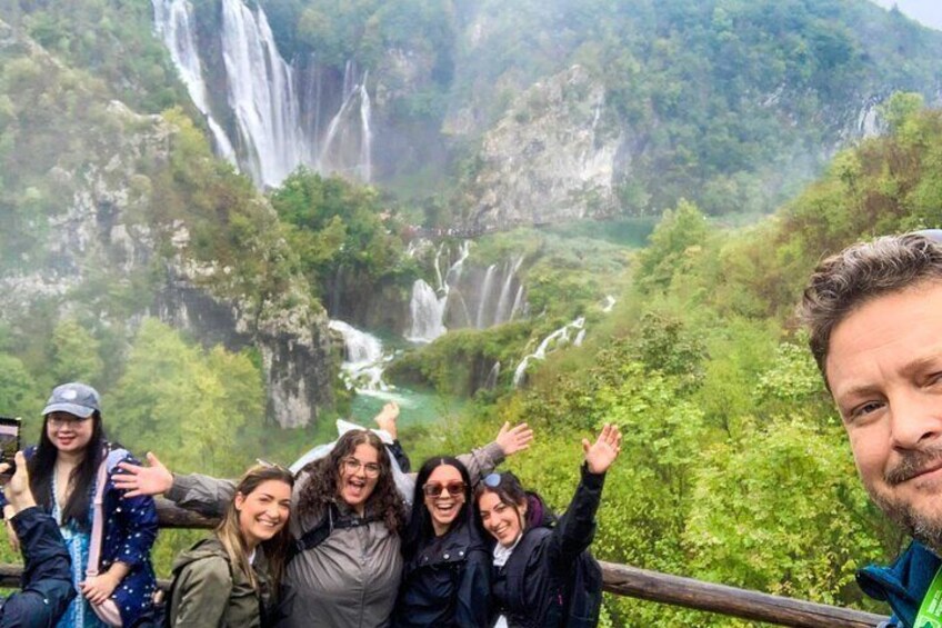 A group of people standing on a bridge with a waterfall in the background. 4