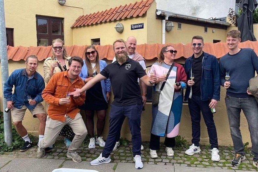 En grupp människor poserar framför en byggnad med ett tak täckt av tegelpannor och en skylt med texten ”Spannen”. 2