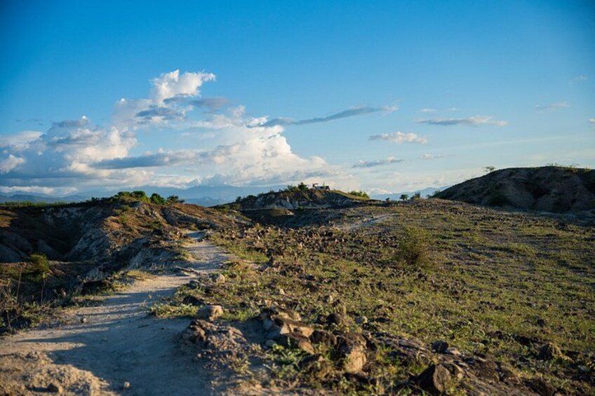 A dirt path winding through a rocky landscape with sparse vegetation under a clear sky. 5