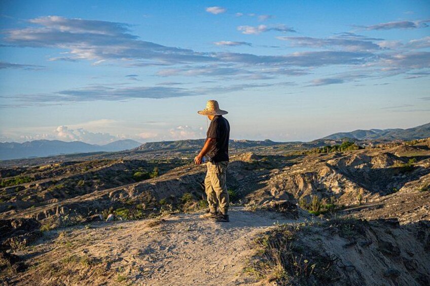 A person standing on a rocky terrain with a mountainous landscape in the background. 3