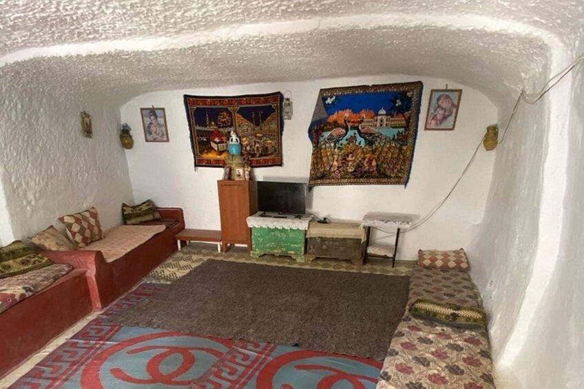 Ein gemütliches Wohnzimmer mit einer Couch, einem Fernseher und dekorativen Wandteppichen. 3