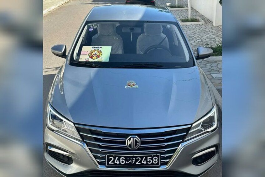 Ein silberner MG Wagen mit einem SIMBA-Aufkleber auf der Windschutzscheibe und dem Kennzeichen 246-2458. 2