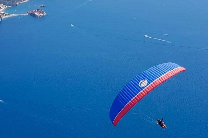 A paraglider over a body of water with a coastline in the background. 3