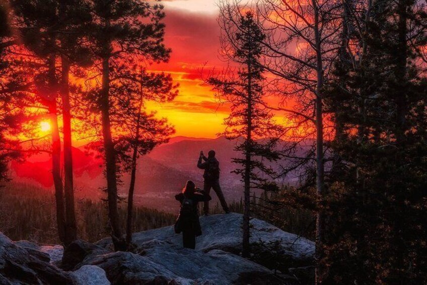 A sunset with two people hiking in a forested area. 4