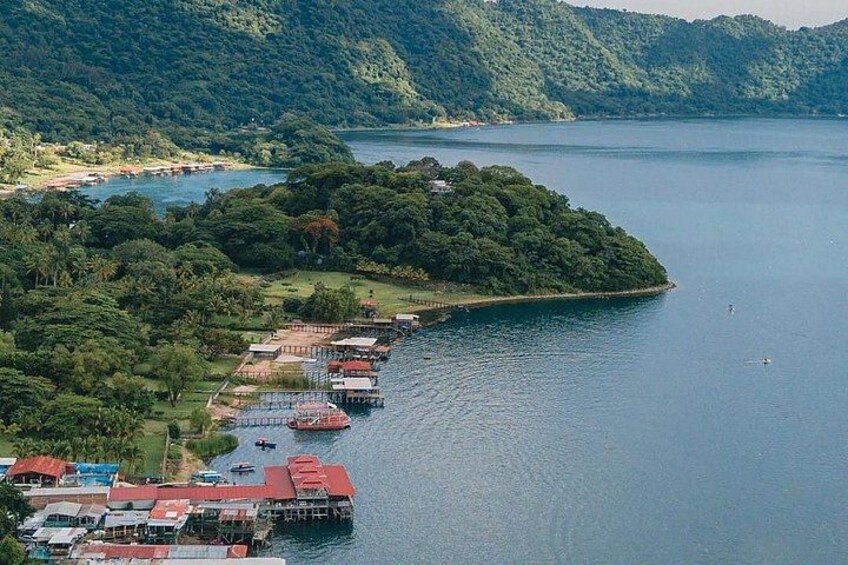 A lake surrounded by forested hills, a small island with buildings, and boats on the water. 2