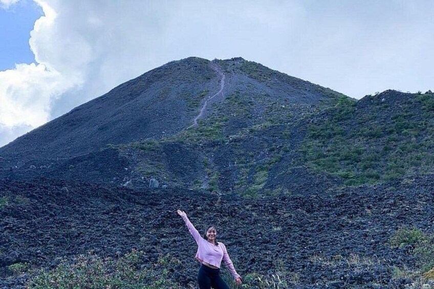 A person standing in front of a mountain with a path leading up. 5