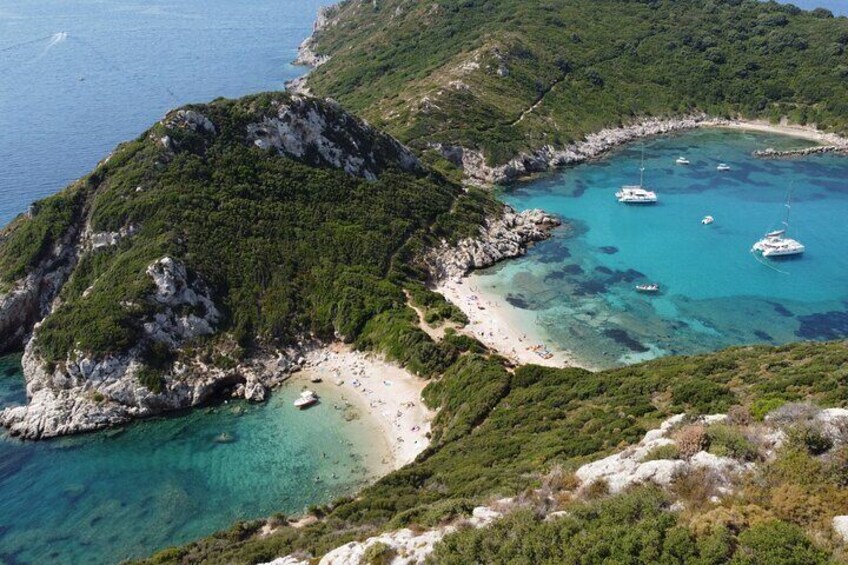 Eine Küstenlandschaft mit klarem türkisblauem Wasser, einem Sandstrand und üppigen grünen Hügeln. 1