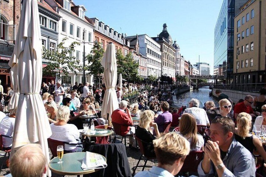 A crowded outdoor café with tables and umbrellas along a canal. 2