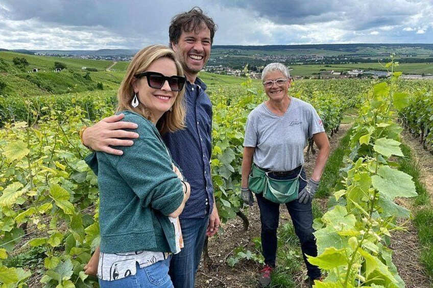 Three people in a vineyard with rows of grapevines. 5