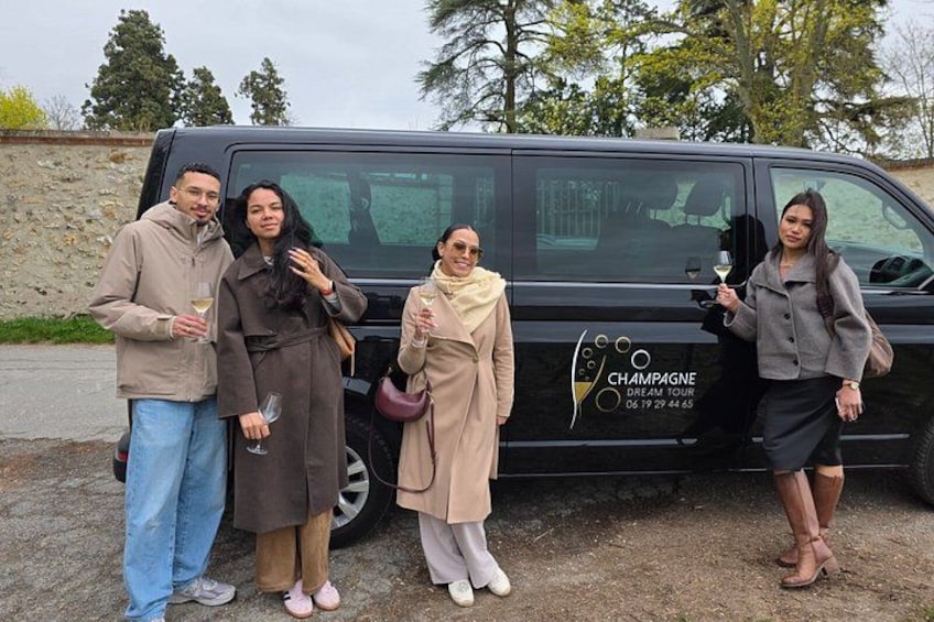 Eine Gruppe von Personen steht vor einem Van mit einem Logo und der Aufschrift 'CHAMPAGNE DREAM TOUR'. 5