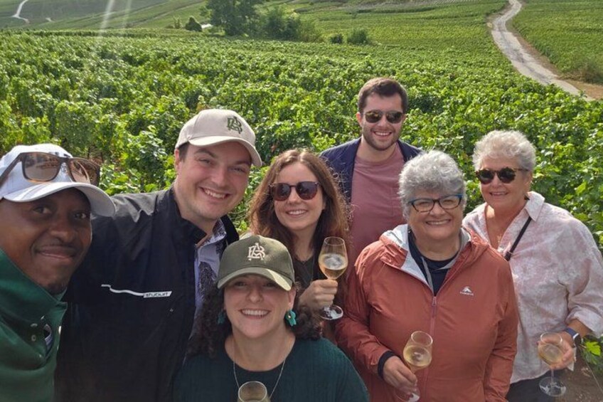 A group of people standing in a vineyard. 3