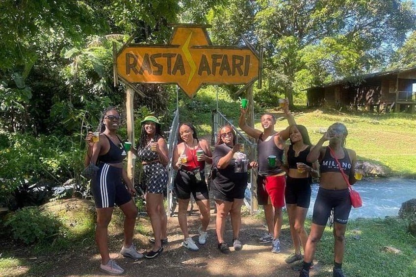 Un grupo de personas de pie frente a un letrero que dice 'RASTA AFARI'. 2