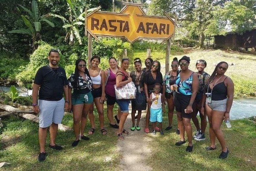 Un grupo de personas de pie frente a un letrero que dice 'RASTA AFARI'. 1