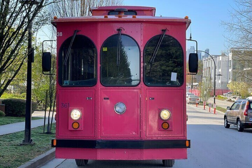 A pink bus with the number 361 parked on a street. 2