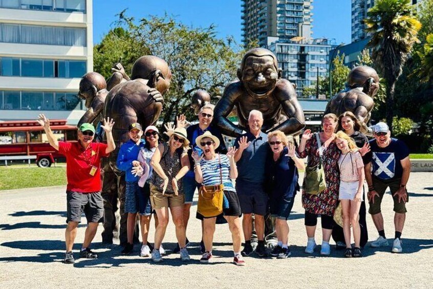 A group of people posing with a large bronze sculpture of a gorilla in an urban park. 4