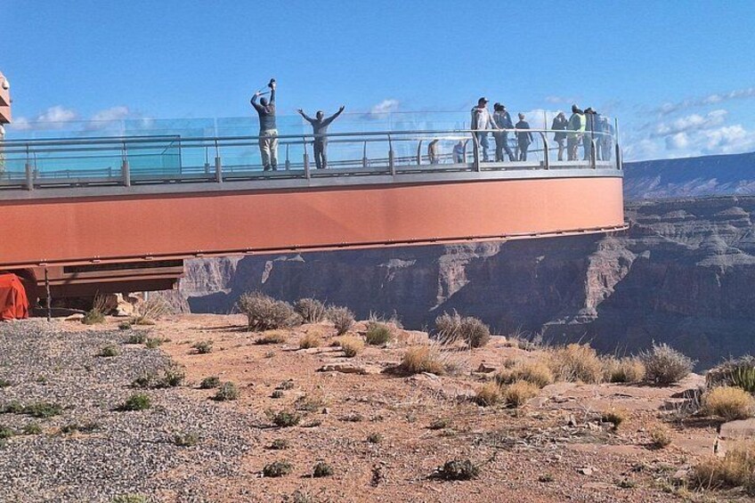 A glass bridge over a canyon with people standing on it. 5