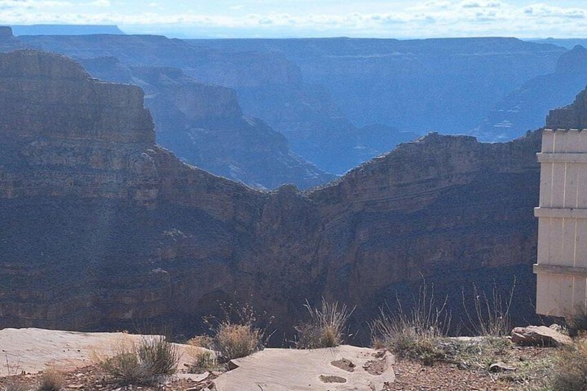 A canyon with layered rock formations and a paved viewing platform. 4