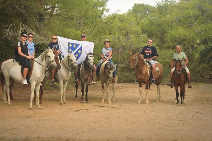 Un gruppo di persone a cavallo in un ambiente naturale, con alberi sullo sfondo. 4