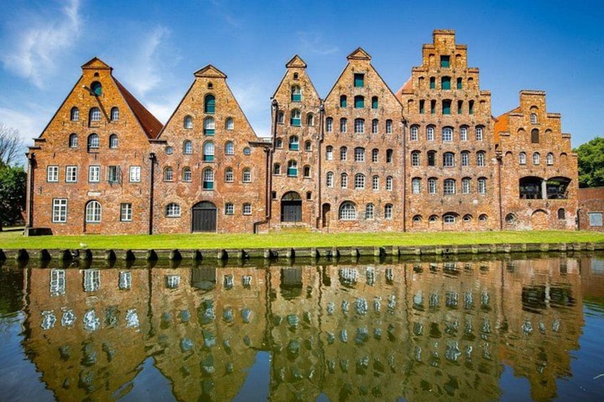 Un grand bâtiment en briques, doté de nombreuses tours et surplombant un plan d’eau dont la surface réfléchit la lumière. 2