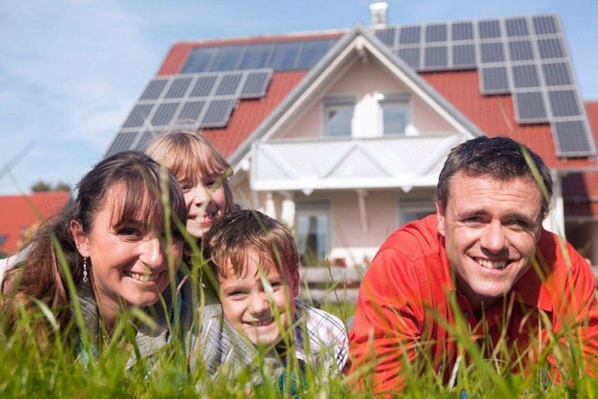 Une famille de quatre personnes se tient devant une maison dont le toit est équipé de panneaux solaires. 5