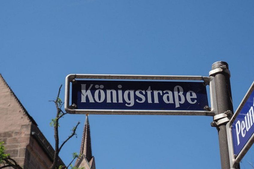 Un panneau de signalisation indiquant la rue Königstraße, avec un ciel bleu clair en arrière-plan. 3