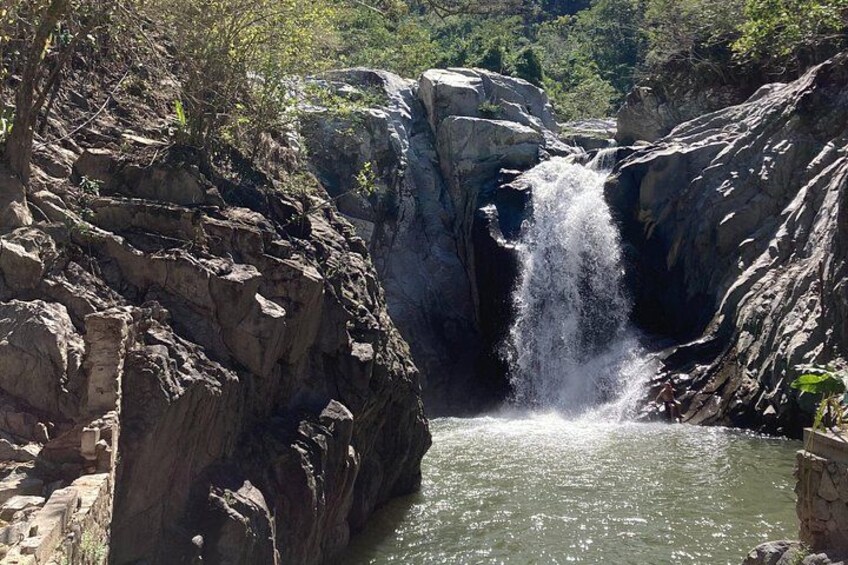 A waterfall cascading down a rocky cliff into a pool of water surrounded by rugged terrain. 4