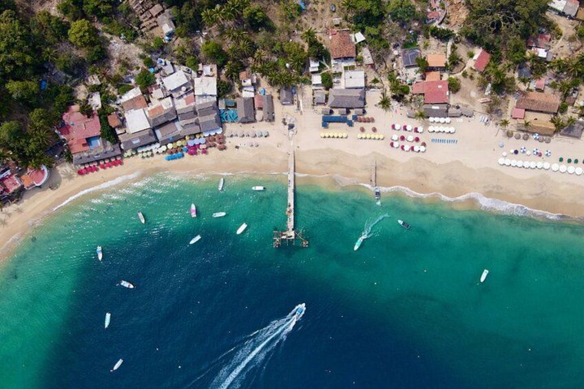 An aerial view of a beach with boats, umbrellas, and buildings. 5