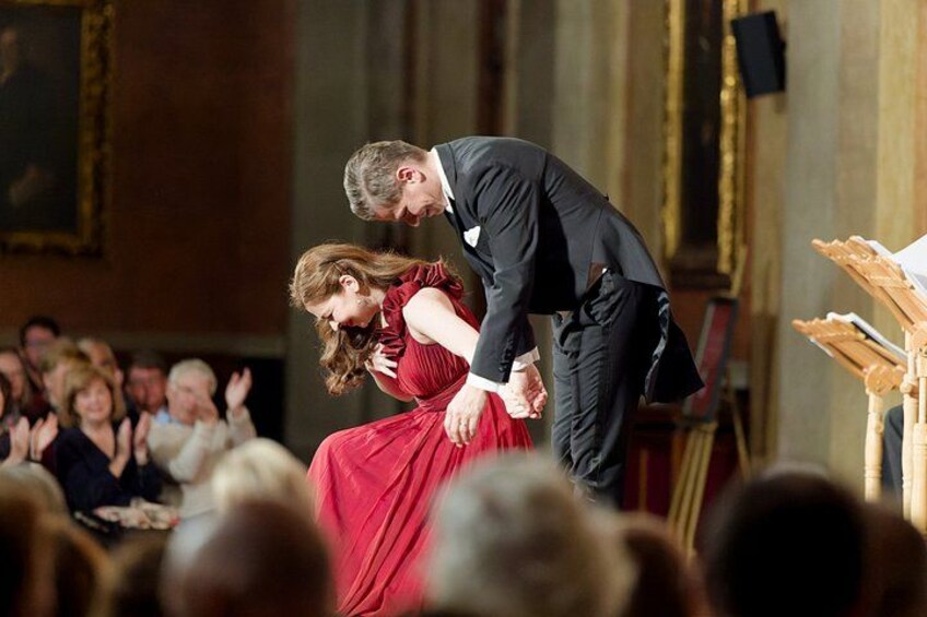 A man and woman in formal attire performing a dance in front of an audience. 4