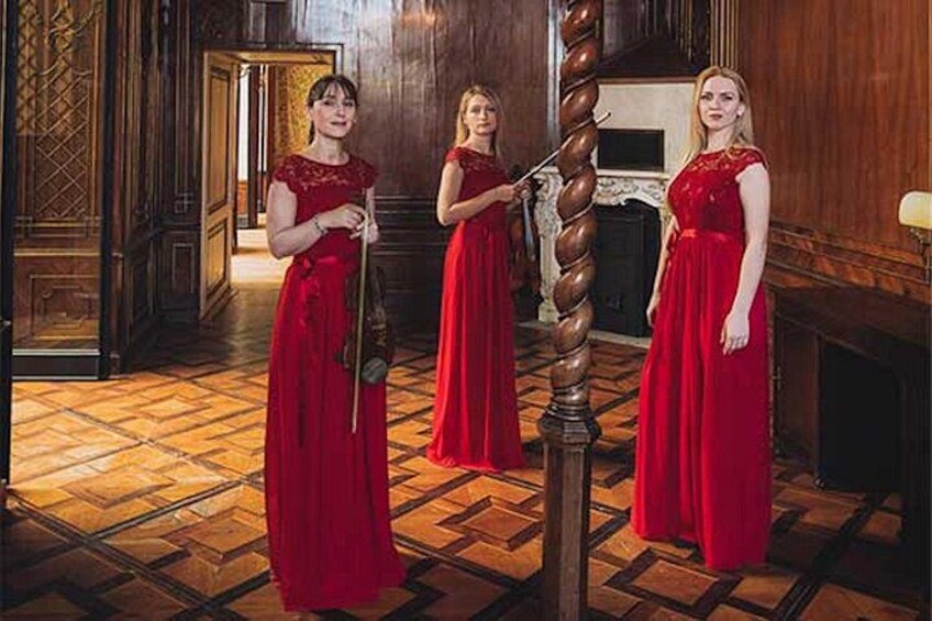 Three women in red dresses standing in a wooden room with a spiral staircase. 5