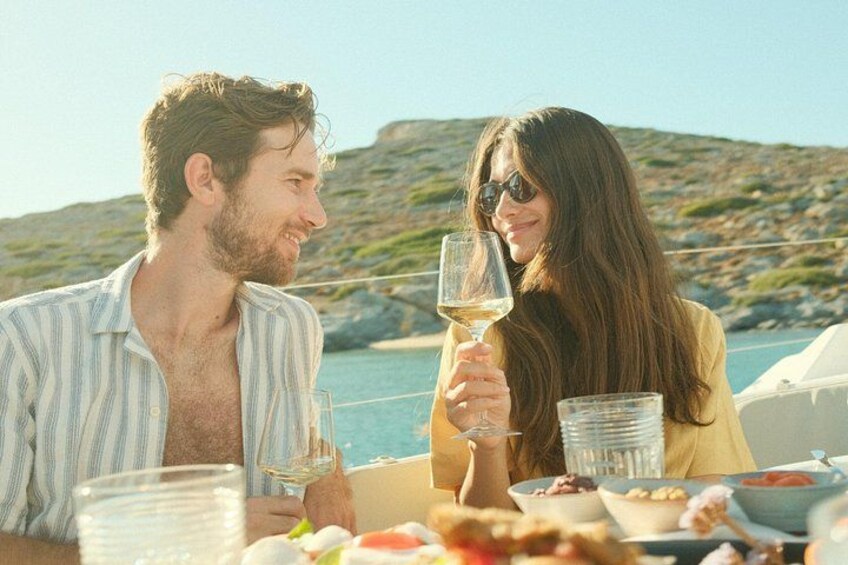 A couple dining on a boat with a rocky coastline in the background. 4