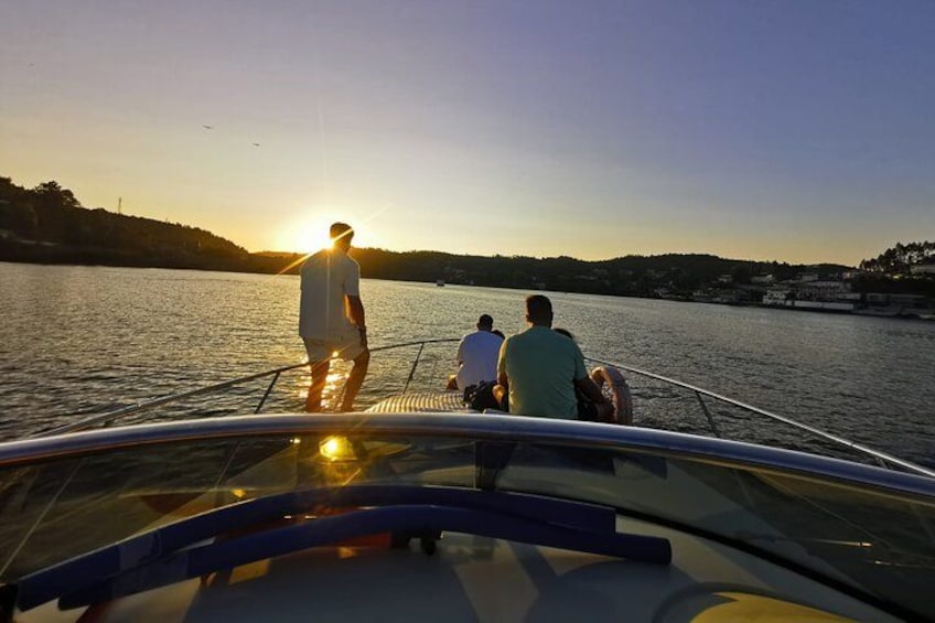 A boat with three people on a calm body of water during sunset. 2