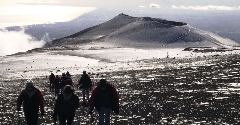 A group of hikers on a snowy mountain with a volcano in the background. 5