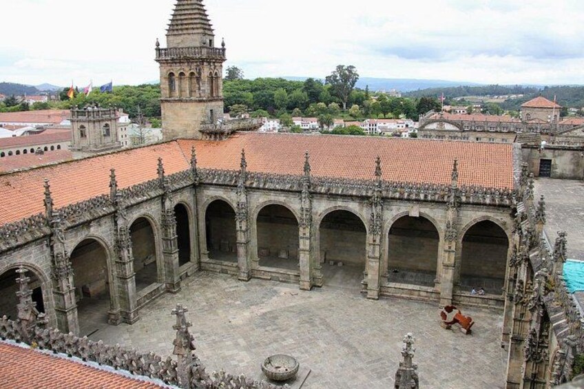 A historical courtyard with arches, a tower, and a statue. 2