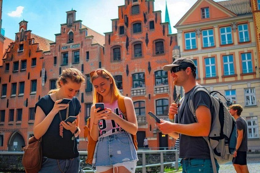 Three people standing in front of historic buildings with red brick facades and a clear sky. 1