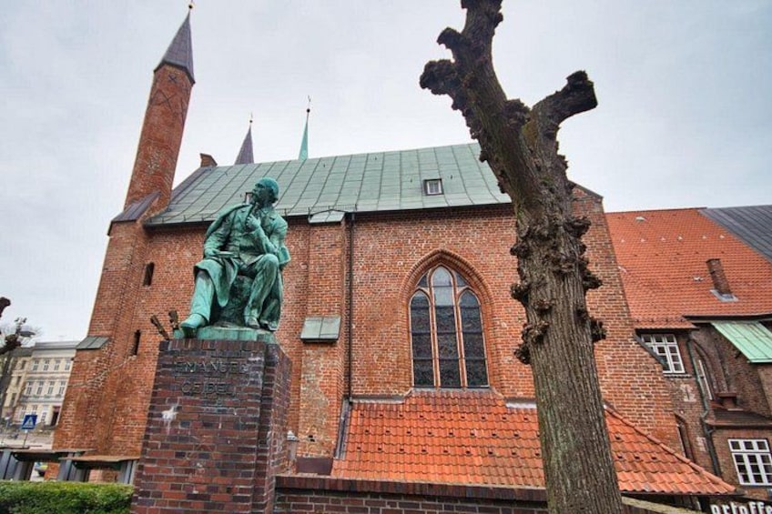 A historic building with a statue, a tall tree, and a brick facade. 5